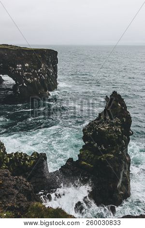 Beautiful Rocky Cliffs And Stormy Ocean In Arnarstapi, Iceland On Cloudy Day