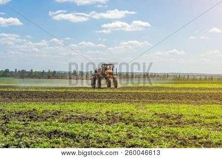 Self-propelled Sprayer Works On A Field Under A Blue Sky With Clouds