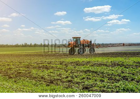 Self-propelled Sprayer Works On A Field Under A Blue Sky With Clouds