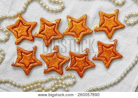 Two Rows Of Eight Decorative Golden Stars Handmade From Dough On A White Fabric Surface With Pearl N