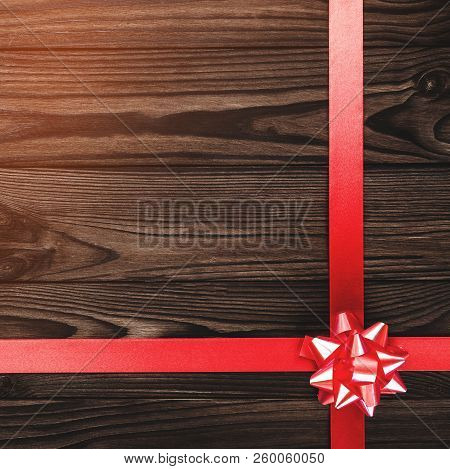 View From Above Of A Merry Christmas Inscription On Dark Brown Wooden Background With Red Ribbon, Gr