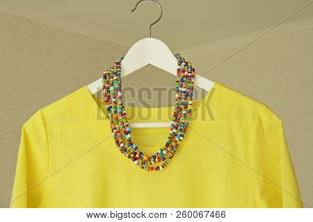 Bright Beads Of Murano Glass Hang On The Background Of A Yellow Summer Dress. Summer Jewelry, Summer