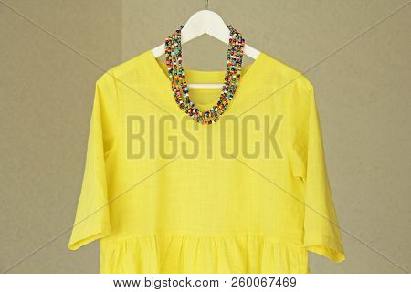 Bright Beads Of Murano Glass Hang On The Background Of A Yellow Summer Dress. Summer Jewelry, Summer