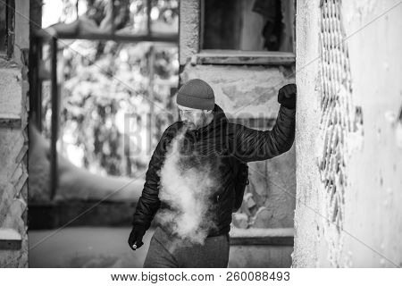 Vape In Life. Young White Man In Red Hat And Black Jacket Letting Off Puffs Of Steam From Electronic