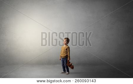 Little waggish kid staying alone in a big empty room with his plush