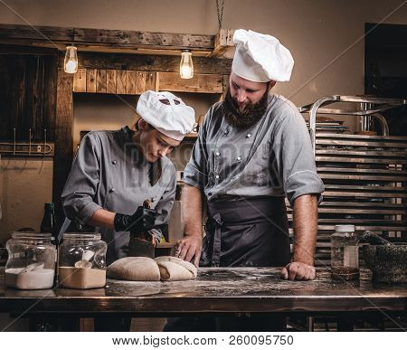 Chef Teaching His Assistant To Bake The Bread In A Bakery.