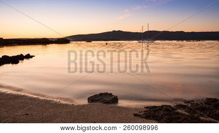 Landscape With A Sailboat Sailing At Sunset On The Shores Of An Island Galicia, Spain