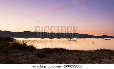 Landscape With A Sailboat Sailing At Sunset On The Shores Of An Island Galicia, Spain