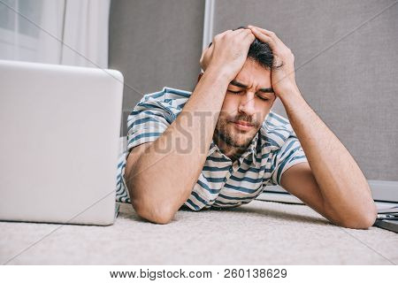 European Stressed Man Looking Exhausted With Headache And Covering His Head With Hands While Lying A