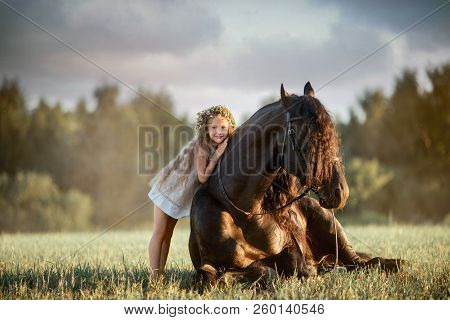 Little  Girl With Black Friesian Stallion At Summer Evening
