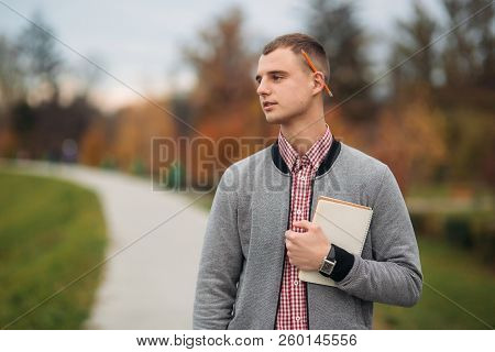 A Cute Student Writes Down His Thoughts In His Notebool Using A Pensil