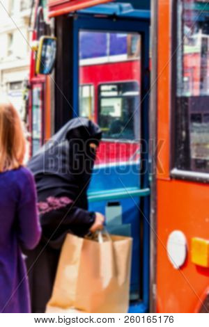 Blurred View Of Elderly Arab Woman In A Burqa Enters The Bus With Purchases In The Paper Bag