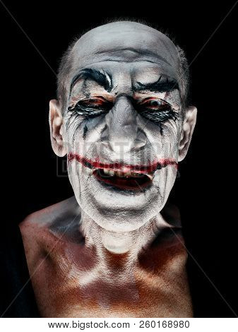 Bloody Halloween Theme: The Crazy Smiling Maniak Face On Dark Studio Background
