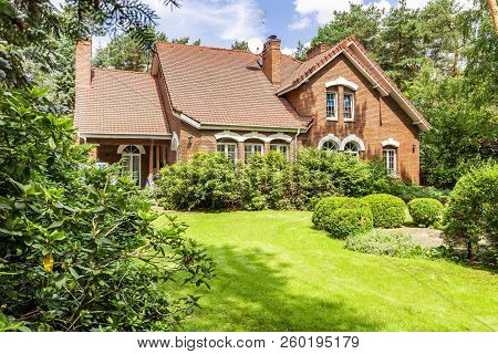 Backround Yard Of A Beautiful English Style House With Bushes And Green Lawn. Real Photo