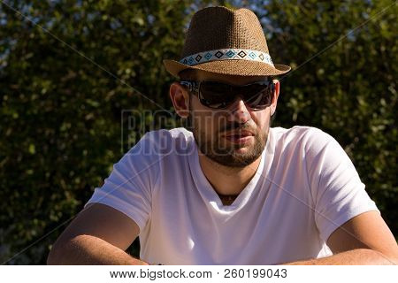 The Man In A Strawy Hat.a Young Man In A Straw Hat And Sunglasses Posing For A Photographer.