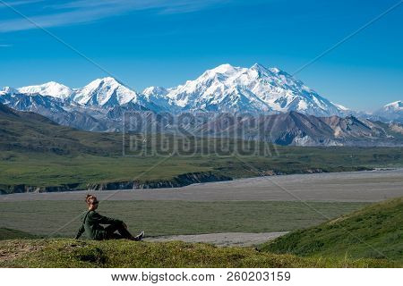 Beautiful Woman Sits On A Hill Looking Out At Mount Denali (mckinley) In Denali National Park. Conce