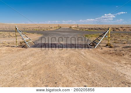 Loney Desert Farmland Road In New Mexico, Featuring A Cattle Guard On The Dirt Gravel Road