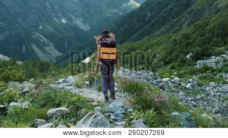 Woman Tourist Descends Down The Hill In A Hike With Beautiful Landscape. Girl With A Backpack On The