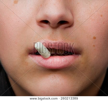 Sensual Female Mouth In Close-up Portrait With Coloured Pill Between Lips