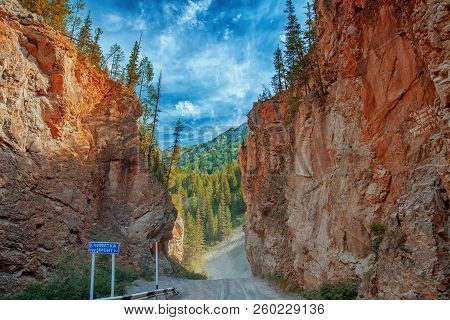 Road Through Narrow Passage In The Rocks. Red Gate On The Chibit River.
