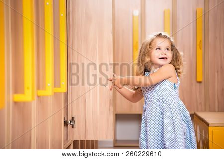 Smiling Adorable Kid Opening Locker In Kindergarten Cloakroom