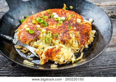 Traditional Swiss hash browns as side dish with leek as closeup in a frying pan 