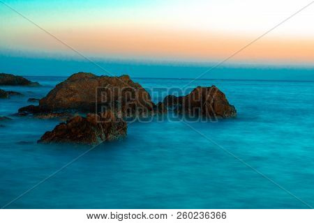 Rocks On A Wavy Sea In The Sunset