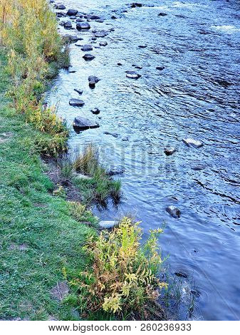 The Beautiful Crooked River With Fall Colored Bushes On Its Banks Flows Through A Canyon Formed From