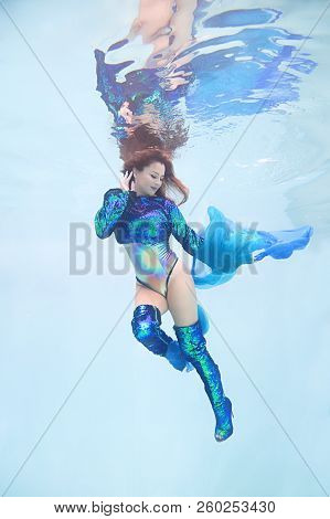 An Underwater Portrait Of A Woman Wearing Green And Blue Sequined Stilletto Boots And Matching Shirt