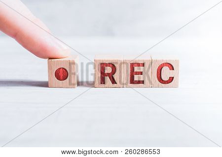 The Abbreviation Rec Formed By Wooden Blocks And Arranged By A Male Finger On A White Table