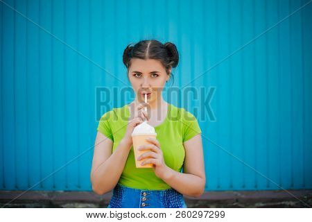 Portrait Of A Girl Against A Bright Blue Wall. Emotional Girl Holding A Plastic Glass With A Refresh