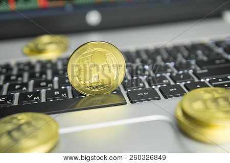 Golden Ripple Coin With Gold Coins Lying Around On A Black Keyboard Of Silver Laptop And Diagram Cha