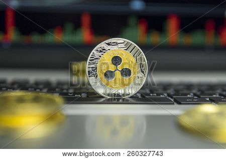 Golden And Silver Ripple Coin With Gold Coins Lying Around On A Black Keyboard Of Silver Laptop And 