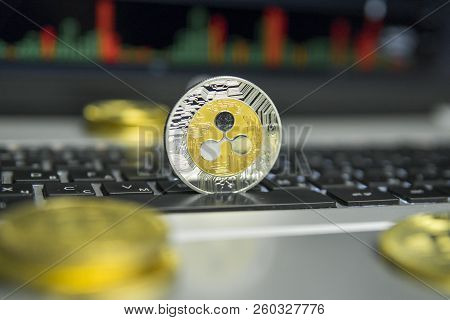 Golden And Silver Ripple Coin With Gold Coins Lying Around On A Black Keyboard Of Silver Laptop And 