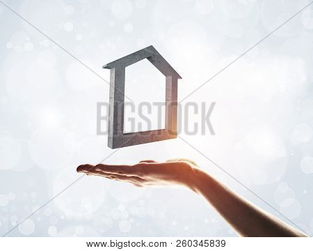 Close Up Of Hand Presenting Stone House Symbol In Palm. Mixed Media
