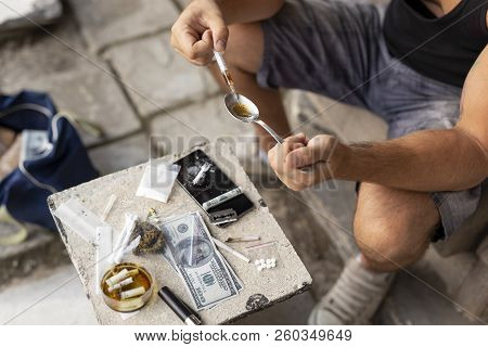 High Angle View Of An Intravenous Junkie Filling Up A Heroin Syringe Injecting Cooked Heroin From A 