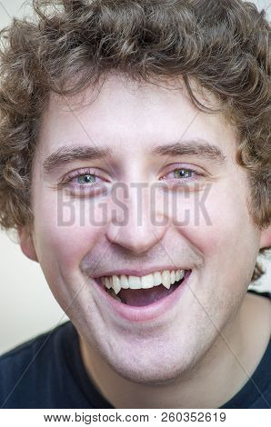 Portrait Of Young Positive Smiling Young Curly Green-eyed Vampire Man On White Background.