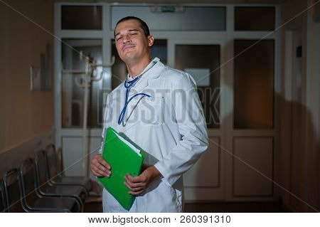 Portrait Of A Beautiful Doctor In The Hospital With A Folder In His Hands