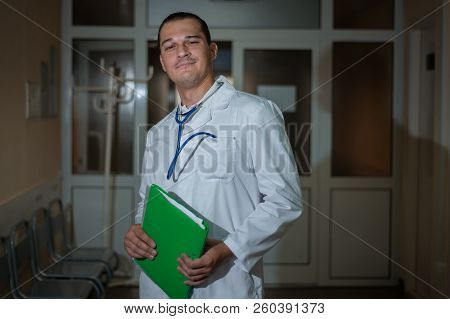 Portrait Of A Beautiful Doctor In The Hospital With A Folder In His Hands