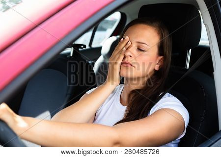 Side View Of A Young Woman Yawning Inside Car