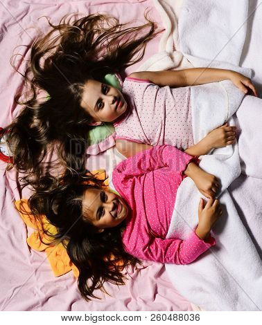 Schoolgirls In Pink Pajamas Wallow On Colorful Pillows, Top View