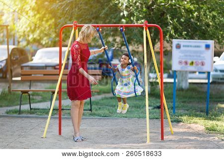 Mom Rolls His Daughter On A Swing.
