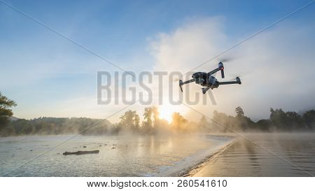 Drone copter with digital camera, blur river on background. Modern technology, UAV concept. Beautiful outdoor non urban scenery.