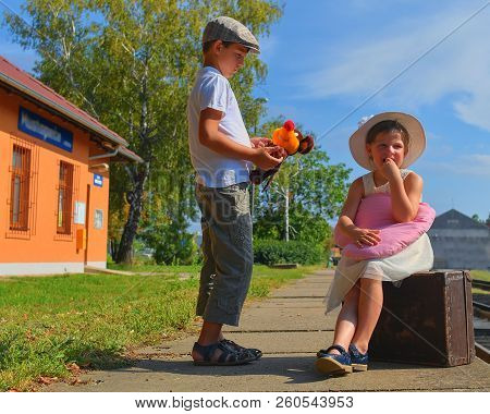 Adorable Little Girl And Boy On A Railway Station, Waiting For The Train With Vintage Suitcase. Trav
