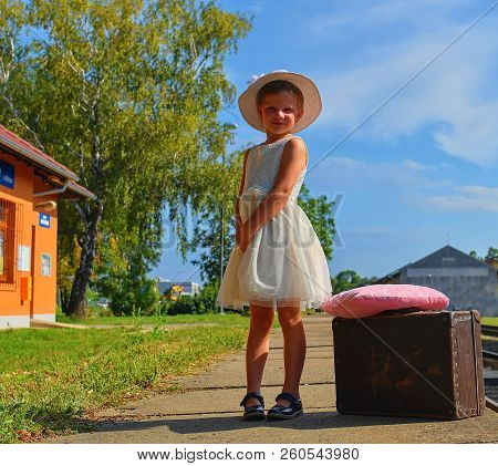 Adorable Little Girl On A Railway Station, Waiting For The Train With Vintage Suitcase. Traveling, H