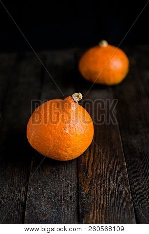 Small Orange Pumpkins On The Dark Wooden Table, Autumn Concept, Harrvest Time. Copy Space.
