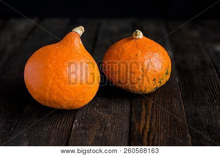 Small Orange Pumpkins On The Dark Wooden Table, Autumn Concept, Harrvest Time. Copy Space.