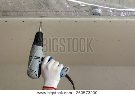 Close-up Of Constructor Worker Hand In Protective Glove With Electrical Cordless Screwdriver Connect