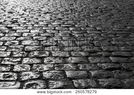 Black And White Picture Of A Close-up Of An Old Road With A Texture Of Stone Sun-drenched At Sunset