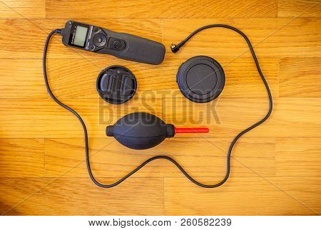 A Wooden Background With A Set Of Photography Accessories Consisting Of A Lens Cap, A Intervalometer